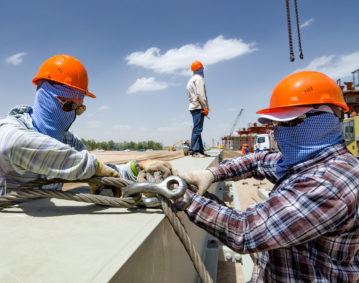 Workers prepare steel for loading. The brigadier does not look.